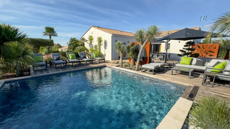 La piscine chauffée de la villa Harmonie, entre palmiers et transats